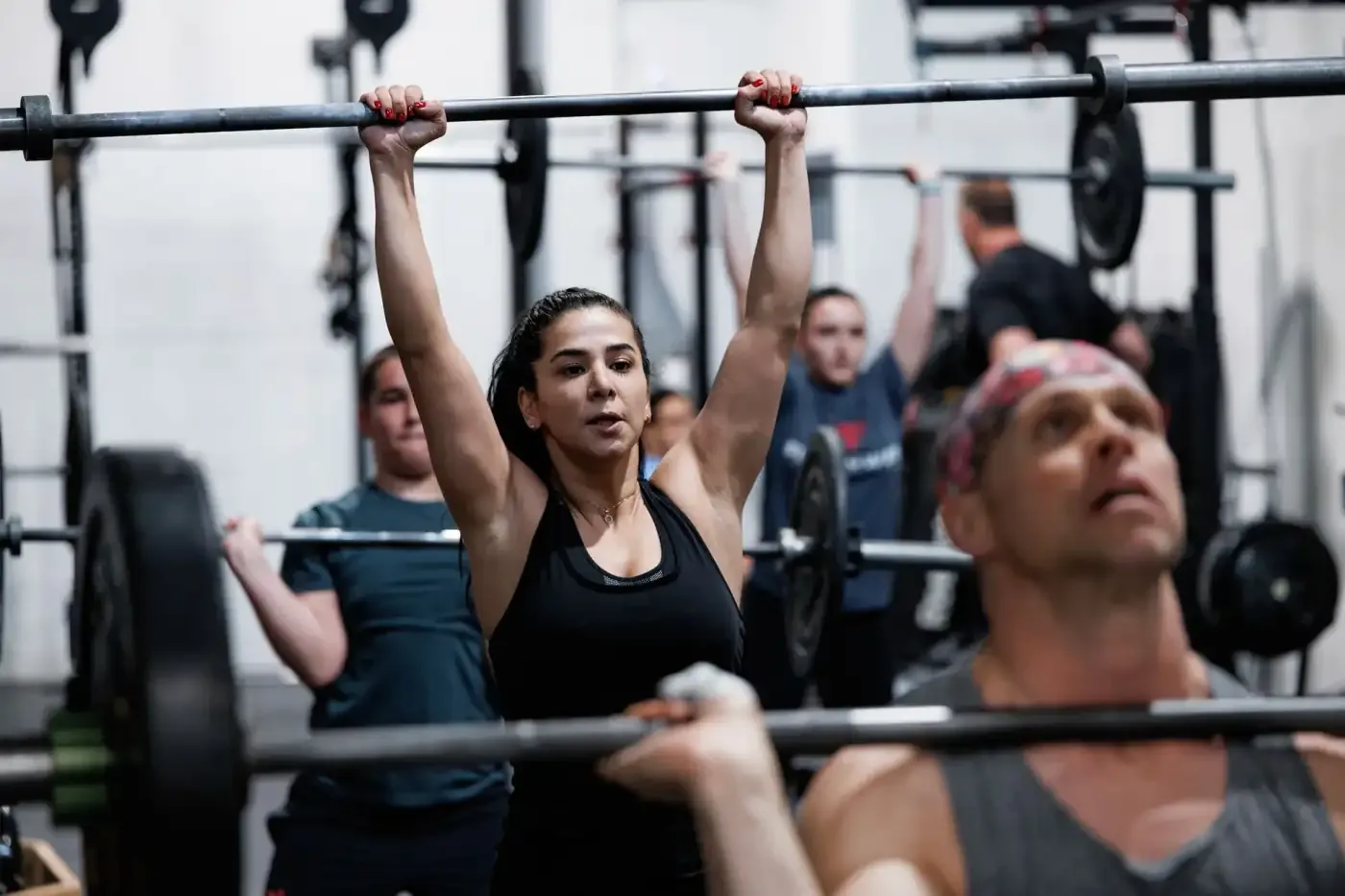 FirePower members pressing barbells overhead together in class